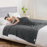 Couverture lestée 4 kg gris foncé posée sur un lit, illustrant un sommeil apaisé avec le modèle enfant.